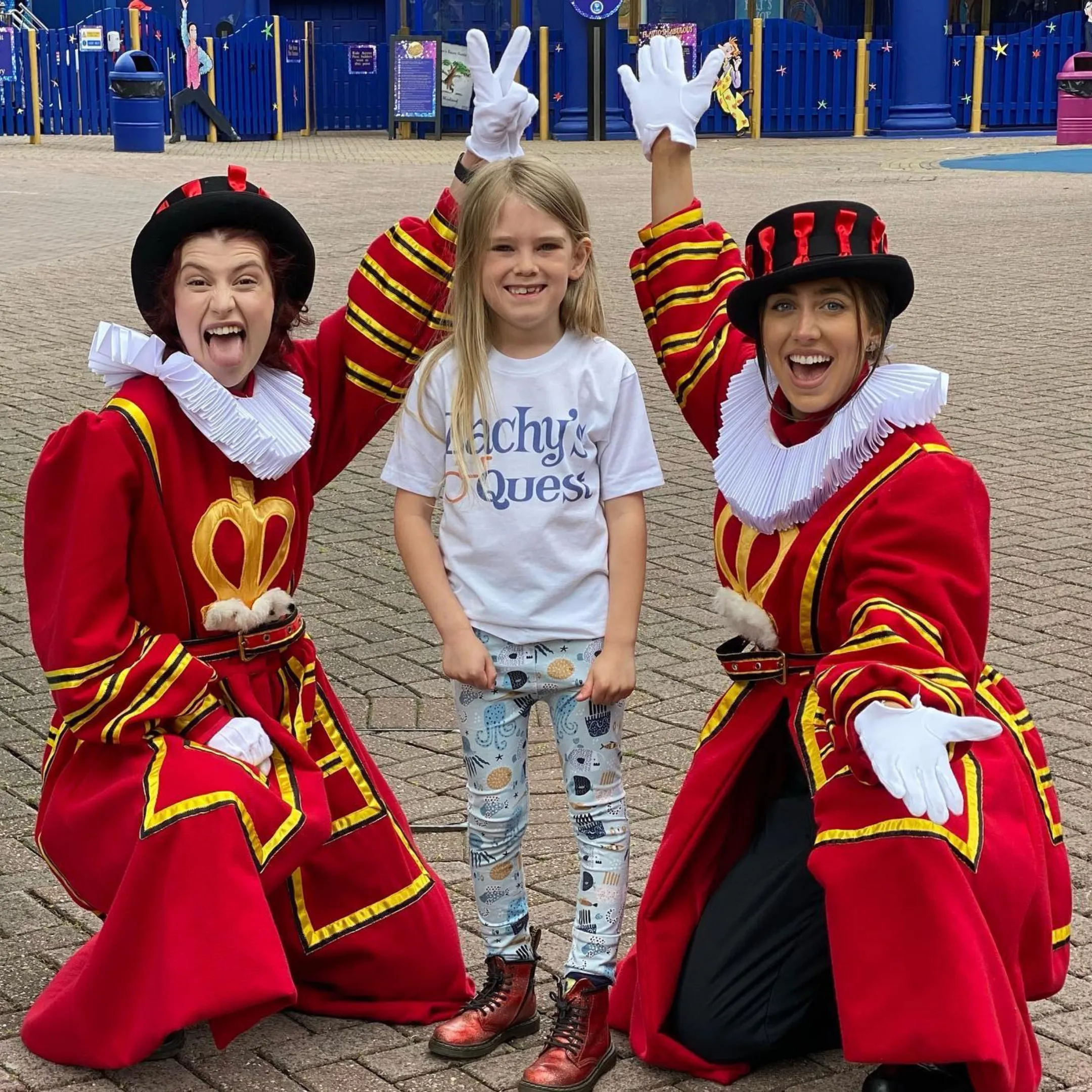 Boy posing with two women dressed in red royal guard regalia. 