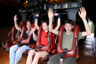 Family putting their arms up preparing for a roller coaster