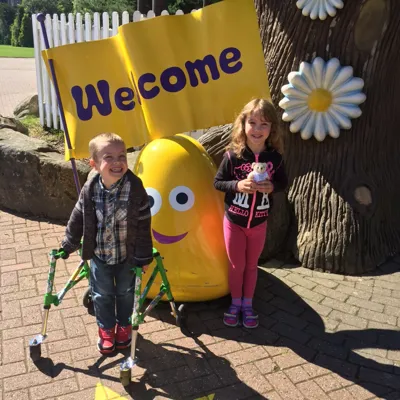 Two happy children smiling next to a welcome sign